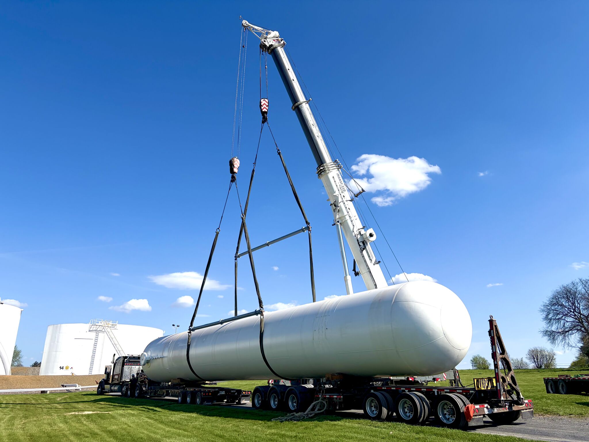 A crane lifting a very large metal LP tank