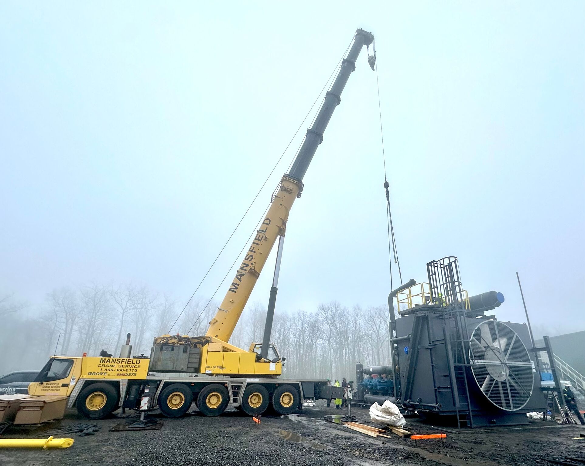 assembling A crane lifting a very large metal LP tank